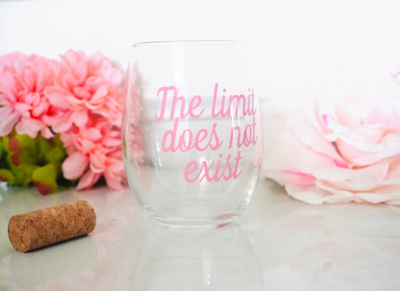 May include: A clear glass wine glass with the pink text "The limit does not exist" printed on the side.