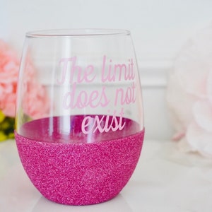 May include: Pink glitter wine glass with the text "The limit does not exist" in pink lettering.