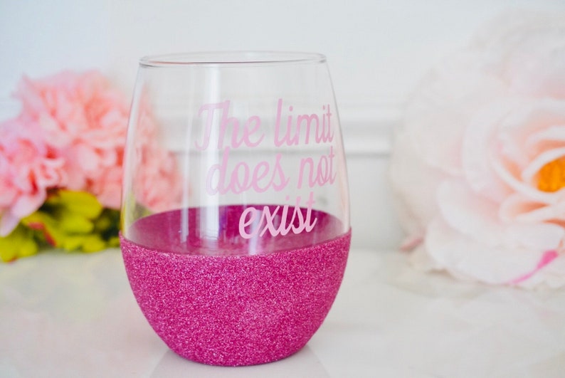 May include: Pink glitter wine glass with the text "The limit does not exist" in pink lettering.
