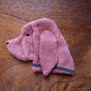 May include: A pink fabric dog toy with black elastic bands around the ears.