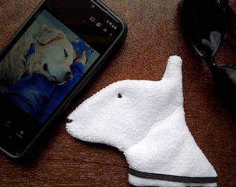 May include: A white, fluffy, plush toy shaped like a dog's head with black eyes. The toy has a black trim around the bottom edge.