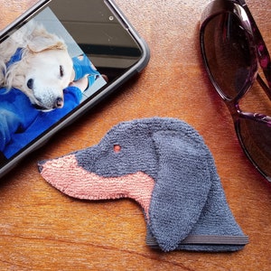 Showing scale of Smudge Dog with two of the many items it can clean and polish: smart phone and eye glasses.