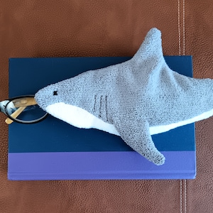 Shark shaped glasses case holding glasses on top of book
