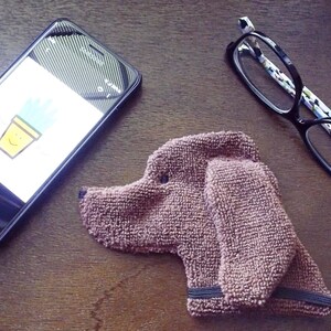 Showing scale of Smudge Dog with two of the many items it can clean and polish: smart phone and eye glasses.