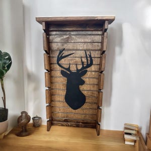 May include: A wooden wall shelf with a deer silhouette design. The shelf has multiple compartments for displaying items.
