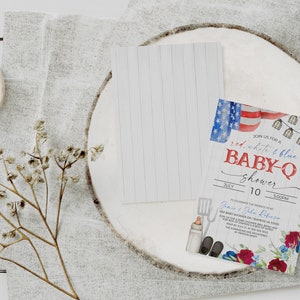 May include: Red, white, and blue baby shower invitation with a watercolor design of an American flag, string lights, and a spatula, bottle, and shoes. The text reads "Join us for a red, white & blue baby-q shower" with the date and time of the event.
