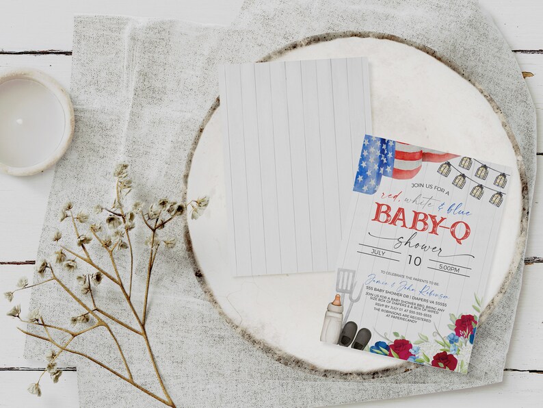 May include: Red, white, and blue baby shower invitation with a watercolor design of an American flag, string lights, and a spatula, bottle, and shoes. The text reads "Join us for a red, white & blue baby-q shower" with the date and time of the event.