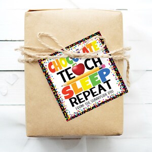 Puede incluir: Una etiqueta de regalo colorida con el texto "Chocolate, Enseñar, Dormir, Repetir" y "De: El PTO de Sunnyside". La etiqueta está decorada con confeti, una manzana roja y un lápiz amarillo.