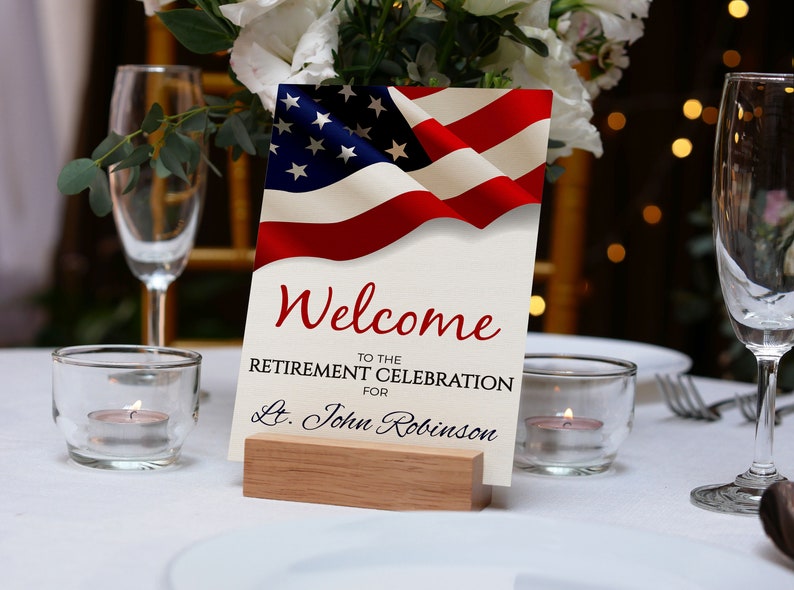 May include: A welcome sign with an American flag design. The sign reads "Welcome to the Retirement Celebration for Lt. John Robinson".