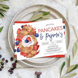May include: A white invitation card with red and blue stripes on the border. The card features a watercolor illustration of pancakes with whipped cream, strawberries, and blueberries. The text on the card reads "Join us for Pancakes & Pajama's!"  "February 10, 10:00 AM"  "To celebrate Jamie's Birthday"  "The Robinson's Home"  "135 Pancake Dr. Syrup, VA 51500"  "RSVP for pancakes & juice"  "Wear your favorite PJs!"  "RSVP with Jamie by Jan 1st at 800-555-0000"