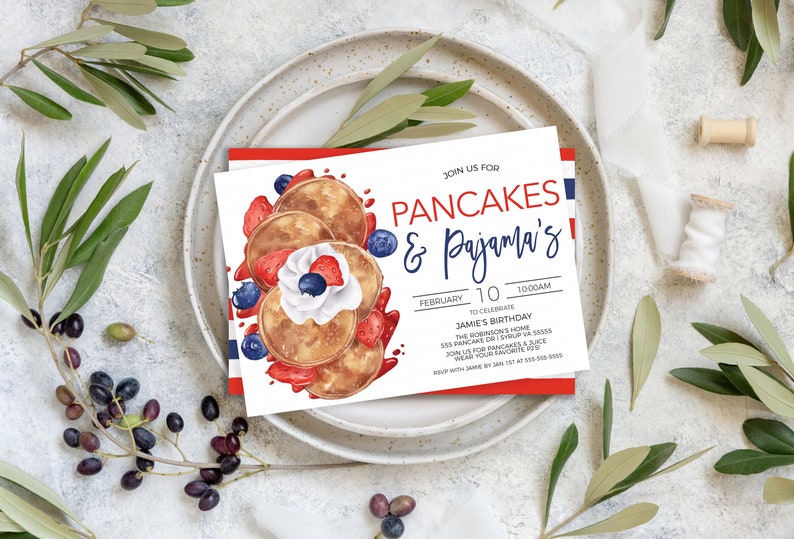 May include: A white invitation card with red and blue stripes on the border. The card features a watercolor illustration of pancakes with whipped cream, strawberries, and blueberries. The text on the card reads "Join us for Pancakes & Pajama's!"  "February 10, 10:00 AM"  "To celebrate Jamie's Birthday"  "The Robinson's Home"  "135 Pancake Dr. Syrup, VA 51500"  "RSVP for pancakes & juice"  "Wear your favorite PJs!"  "RSVP with Jamie by Jan 1st at 800-555-0000"