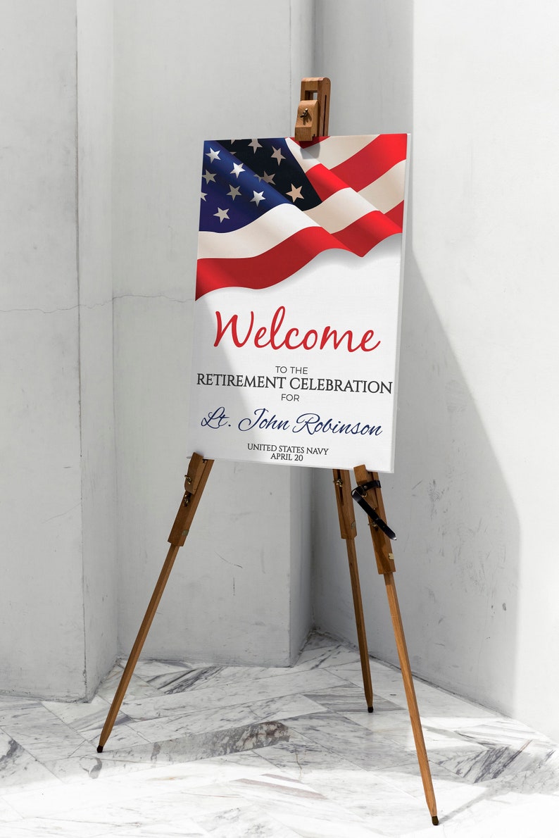 May include: Welcome to the Retirement Celebration for Lt. John Robinson, United States Navy, April 20. A white sign with red, white, and blue text is displayed on a wooden easel with an American flag in the background.
