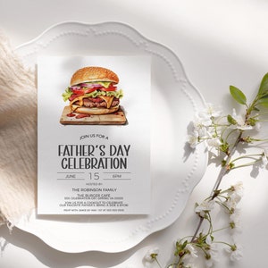 May include: A white card with a Father's Day celebration invitation. The card features a watercolor illustration of a hamburger with lettuce, tomato, onion, and cheese. The text on the card reads "Join us for a Father's Day Celebration, June 15, 6PM, Hosted by The Robinson Family, The Burger Cafe, 555 Celebration Dr, Spring VA 55555, Join us for a cookout to celebrate our favorite Father's! Bring a side & YOB! RSVP with Jamie by May 1st at 555-555-5855."