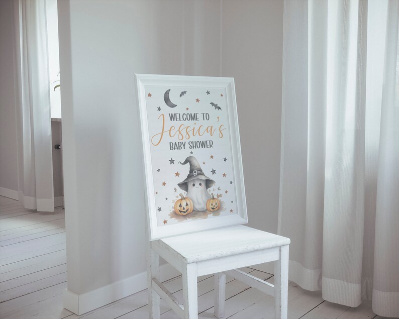 K&ouml;nnte beinhalten: Ein wei&szlig;es Schild mit schwarzem Rahmen und einer Babyparty-Ank&uuml;ndigung zum Thema Halloween. Das Schild lautet "Willkommen zur Babyparty von Jessica" und zeigt einen Geist, der einen Hexenhut tr&auml;gt und zwei K&uuml;rbisse h&auml;lt.