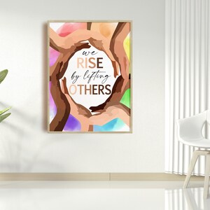 Op de afbeelding: Een motiverende poster met een cirkel van handen in verschillende huidtinten, met de tekst "we rise by lifting others".