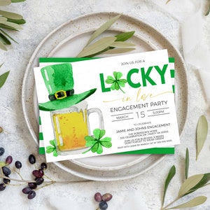 May include: An engagement party invitation with a St. Patrick's Day theme. The invitation features a green leprechaun hat, a mug of beer, and shamrocks. The text reads "Lucky in Love" and includes event details.
