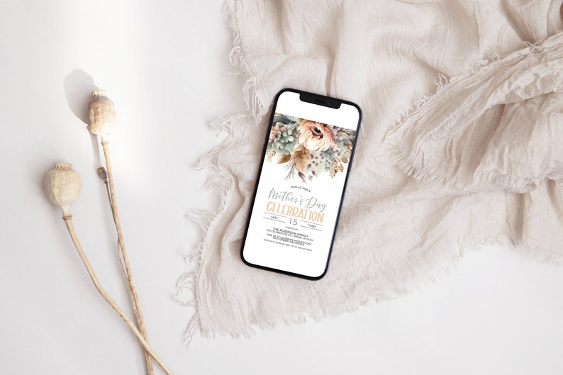 May include: A smartphone displaying a digital invitation for a Mother's Day celebration. The invitation features a watercolour floral design in shades of beige, brown, and green. The text reads "Mother's Day Celebration" with the date "May 15".