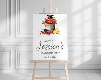 May include: A graduation party welcome sign on an easel. The sign features a watercolor illustration of crabs in a pot, lemons, and graduation caps. The text reads "Welcome to Jessica's Graduation Party June 01 2026."