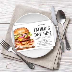 May include: A white invitation card with a watercolor illustration of a hamburger. The text on the card reads "Join us for a Father's Day BBQ" with the date and time of the event.