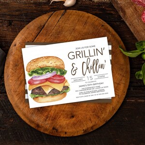 May include: A white invitation card with brown text that reads "Join us for some Grillin' & Chillin'" and details for a birthday party. The card features a watercolour illustration of a hamburger with lettuce, tomato, onion, cheese, and a beef patty.