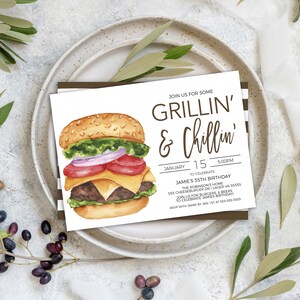 May include: A white invitation card with brown text that reads "Join us for some Grillin' & Chillin'" and details for a birthday party. The card features a watercolour illustration of a hamburger with lettuce, tomato, onion, cheese, and a beef patty.