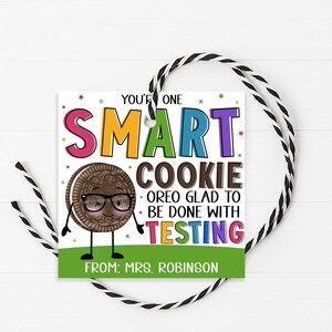 May include: A square gift tag with black and white twine featuring a cartoon chocolate sandwich cookie wearing glasses. The text reads: YOU'RE ONE SMART COOKIE OREO GLAD TO BE DONE WITH TESTING FROM: MRS. ROBINSON, accented with colorful stars.
