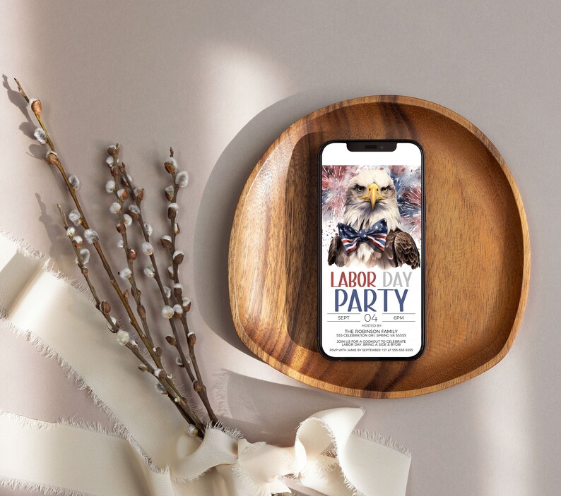 May include: A wooden tray with a smartphone displaying a Labor Day party invitation. The invitation features a bald eagle with a red, white, and blue bow tie and the text "Labor Day Party".
