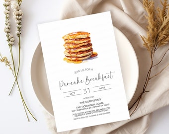 May include: A white invitation card with a watercolor illustration of a stack of pancakes with syrup. The text on the card reads "Join us for a Pancake Breakfast" with the date "Oct 31" and time "4PM". The invitation is for a birthday celebration at "The Robinson's" home.