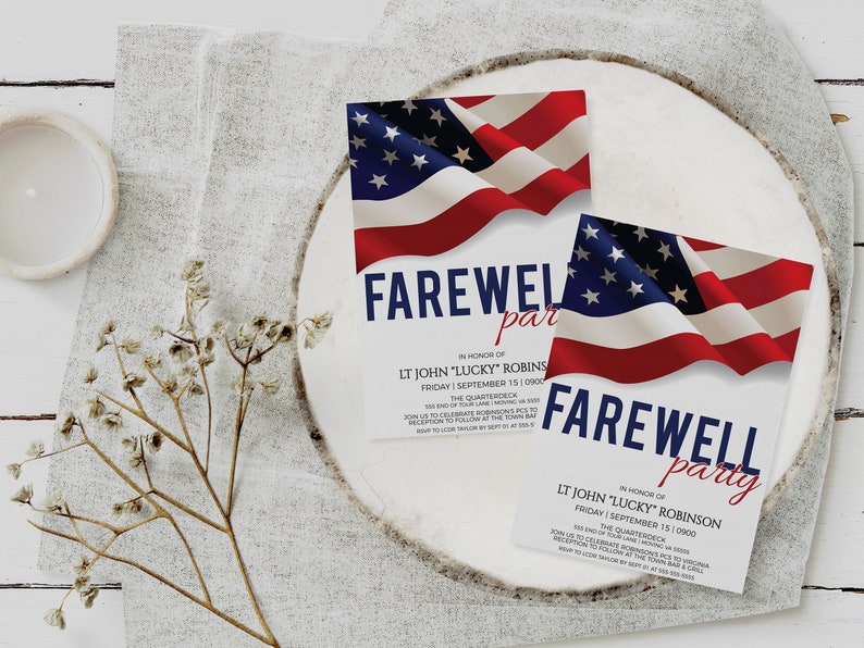 May include: Two white cards with red, white, and blue American flag designs. The cards are on a white wooden surface. The text on the cards reads "Farewell party" in honor of "LT John "Lucky" Robins" and "LT John "Lucky" Robinson".