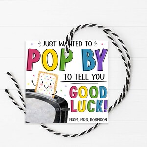 May include: A square gift tag with a black and white string. The tag features the text "Just wanted to pop by to tell you good luck!" in colorful letters. A cartoon Pop-Tart pops out of a toaster.