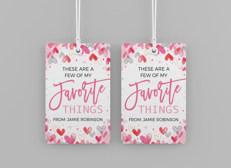 K&ouml;nnte beinhalten: Zwei rosa und wei&szlig;e Geschenkanh&auml;nger mit einem Aquarell-Herz-Muster. Der Text auf den Anh&auml;ngern lautet "Das sind ein paar meiner Lieblingssachen." und "Von: Jamie Robinson".