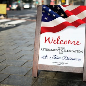 May include: A wooden A-frame sign with an American flag design and the text "Welcome to the Retirement Celebration for Lt. John Robinson United States Navy April 20".