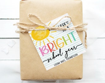 May include: A gift tag with a sun and the text "Here's to a bright school year" with the name "Mrs. Thompson" at the bottom.