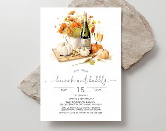 Könnte beinhalten: Eine weiße Einladungskarte mit einer Aquarell-Illustration einer Champagnerflasche, zwei Gläsern, Kürbissen und Herbstlaub. Der Text auf der Karte lautet "Schließen Sie sich uns zum Brunch und Sekt an" und enthält Details für eine Geburtstagsfeier.
