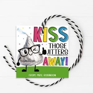 May include: A square gift tag with a cartoon Hershey's Kiss character wearing glasses and giving a thumbs up. The tag reads "Kiss Those Jitters Away!" in colorful text, with the name "Mrs. Robinson" at the bottom. A black and white string is attached.