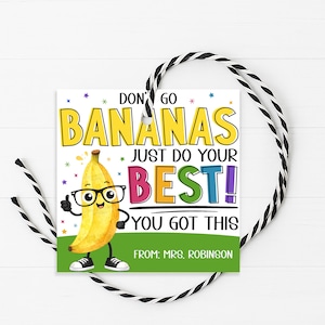 May include: A square gift tag with a cartoon banana wearing glasses and the text "DON'T GO BANANAS JUST DO YOUR BEST! YOU GOT THIS." The tag has a green bottom and is tied with a black and white string. The text "FROM: MRS. ROBINSON" is at the bottom.