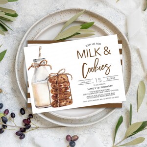 May include: A white invitation card with brown stripes on the edges. The card has a watercolor illustration of a bottle of milk and a stack of chocolate chip cookies. The text on the card reads "Join us for Milk & Cookies" and "January 15, 5:00PM to celebrate Jamie's 1st Birthday".