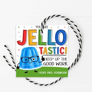 May include: A square gift tag with a colorful design. The text reads "YOU ARE JELLO TASTIC! KEEP UP THE GOOD WORK" with a cartoon blue jelly character. The tag is decorated with stars and a green base. A black and white string is attached.
