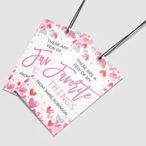 K&ouml;nnte beinhalten: Ein wei&szlig;es Geschenkanh&auml;nger mit einem rosa Aquarell-Herz-Muster. Der Anh&auml;nger hat den Text "Das sind ein paar meiner Lieblingsdinge" und "Von: Jamie Robinson".