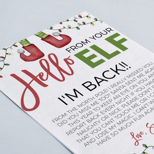 May include: A white card with red and green text that reads "Hello Elf I'm Back!!"  The card has a festive Christmas theme with illustrations of elf shoes, Christmas lights, and a snowflake. The text on the card is a message from an elf to a child.