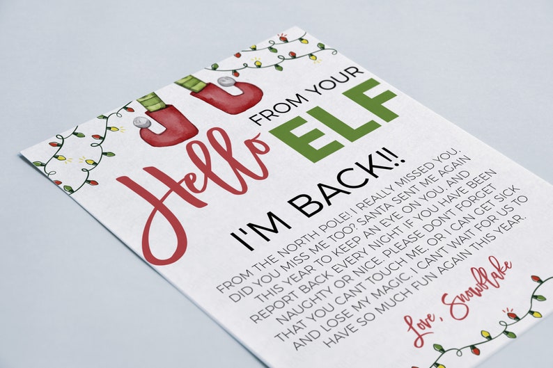 May include: A white card with red and green text that reads "Hello Elf I'm Back!!"  The card has a festive Christmas theme with illustrations of elf shoes, Christmas lights, and a snowflake. The text on the card is a message from an elf to a child.