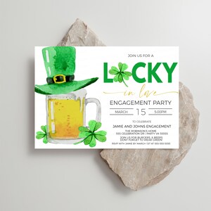 May include: An engagement party invitation with a watercolor design. The invitation features a green leprechaun hat atop a beer mug, shamrocks, and the words "Lucky in Love." The date and time of the party are also included.