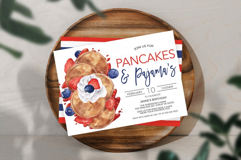 May include: A white invitation card with a watercolor illustration of pancakes topped with whipped cream, strawberries, and blueberries. The text on the card reads "Join us for Pancakes & Pajama's!"  "February 10, 10:00 AM"  "To Celebrate Jamie's Birthday"  "The Robinson's Home"  "555 Pancake Dr | Syrup VA 55555"  "Join us for pancakes & juice"  "Wear your favorite PJs"  "RSVP with Jamie by Jan 1st at 555-555-5555"
