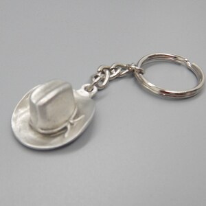 May include: A silver cowboy hat keychain with a silver key ring.