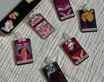 May include: Six colorful enamel pins with different designs and text. The pins feature illustrations of books, skulls, and hearts. The text on the pins includes "The Spice", "The Reader", "The Fated Mates", "Friends to Lovers", and "The Vampire Romance".