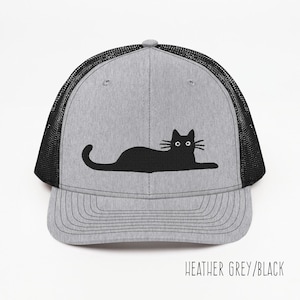 May include: A heather grey and black trucker hat with a black silhouette of a cat lying down on the front.