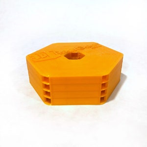 May include: A bright orange hexagonal 3D printed object with a hole in the center. The object has the text "3D Tech" printed on the top.