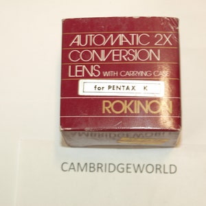 May include: A red box with white text that reads "Automatic 2x Conversion Lens with Carrying Case for Pentax K Rokinon".