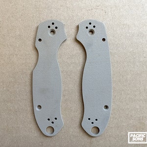 May include: Two beige plastic knife scales with multiple holes for mounting hardware. The scales have a textured surface.