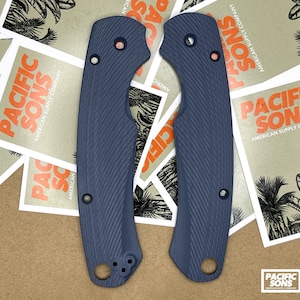 May include: Two dark blue knife scales with a textured pattern. The scales have a rounded shape and are designed to fit a knife handle.